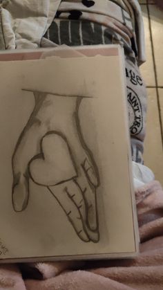 a drawing of a hand on a piece of paper next to a pile of blankets