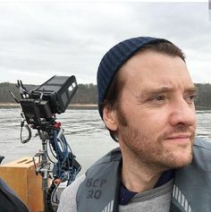 a man with a blue hat is on a boat in the water and has his camera attached to his head