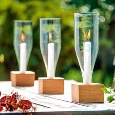 three candles are placed in wooden holders on a table