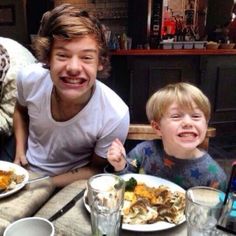 two young boys sitting at a table with plates of food in front of them smiling