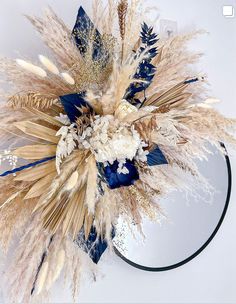 an arrangement of dried flowers and feathers on a white surface with a black circle around it