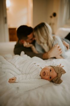 a man and woman laying on top of a bed next to a small baby doll