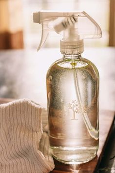 a bottle of liquid sitting on top of a wooden table next to a white glove