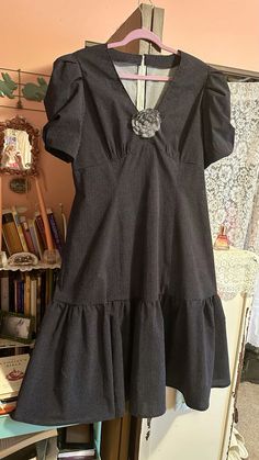 a dress hanging on a clothes rack in front of a bookcase and bookshelf