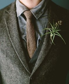 a close up of a person wearing a suit with a plant in his lapel