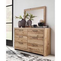 a wooden dresser with two vases and a mirror