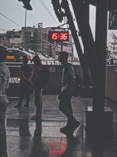 some people are standing on the sidewalk in the rain