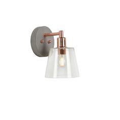 a wall light with a clear glass shade on the side and copper metal fittings