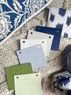 four different shades of blue and green on a tablecloth with plates, bowls and napkins