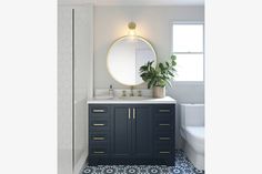 a bathroom with blue and white tile flooring and a round mirror above the sink