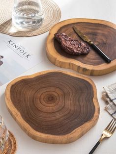 two wooden plates sitting on top of a table next to silverware and utensils