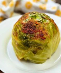 a white plate topped with an artichoke covered in sauce