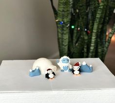 two small figurines sitting on top of a white box next to a christmas tree