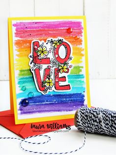 a card with the word love painted on it next to a spool of thread