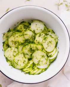 a white bowl filled with cucumbers on top of a table