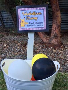 a bucket filled with balloons and a sign