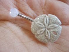 a close up of a person's hand holding a piece of silver glittered jewelry