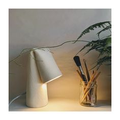 a lamp that is next to a vase with some pens and pencils in it