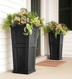 two black planters sitting on the side of a house