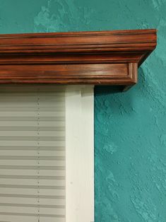 a wooden window frame with blinds on the top and bottom, against a blue wall