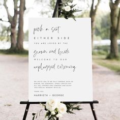 a wedding sign with flowers and greenery on it