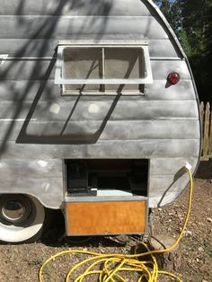 an old camper is being worked on with a yellow hose attached to the door