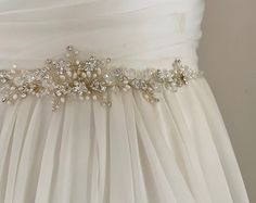 "Elegant and more beautiful in person, this delicate sash is intricately hand wired with Freshwater pearls & sparkling crystals in a whimsical floral design. A gorgeous sash to complete your unique wedding look. READY TO SHIP DETAILS: * Beading Measures 16.5\" (Length) 8.5\" x 1.5\" (Design) * Attached at ends to imported French satin ribbon in choice of colors. * Total sash length 3 yards. * Offered in Silver * Matching Jewelry & Hairpieces COLLECTION: Sashes, Jewelry, Hairpiece & Vintage Beade White Pearl Embellished Sashes For Wedding, Silver Belts, Wedding Sash Belt, Sash Belts, Wedding Sash, Wedding Belts, Bridal Sash, Matching Jewelry, Floral Vine