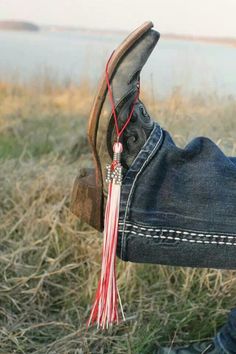 a pair of shoes with a tassel hanging from the side, in front of a body of water