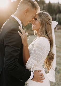 a bride and groom embracing each other in front of the sun