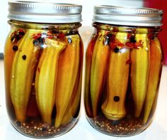 two jars filled with pickles sitting on top of a table