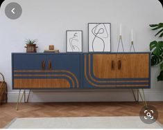 a blue and brown sideboard with two pictures on top of it next to a potted plant