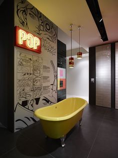 a yellow bath tub sitting next to a wall covered in comic strip art on it