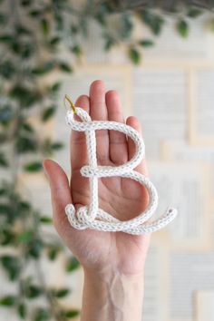 a hand holding up a small white object with the letter b in it's middle