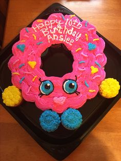 a birthday cake decorated with pink frosting and blue icing, on top of a black tray