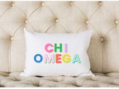 a pillow with the word chii omega on it sitting on a couch