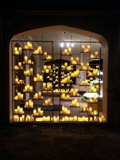 many candles are lit in front of a window with an arched doorway at night time