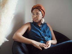 a woman sitting in a chair wearing a turban and looking off into the distance