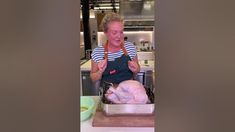 an older woman holding a large piece of meat in her hands while standing next to a turkey