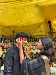 a man and woman standing next to each other in front of a yellow tent