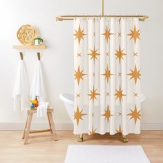 a bathroom with a white rug and gold stars on the shower curtain, next to a bathtub