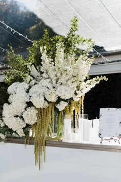 white flowers and greenery are arranged in vases