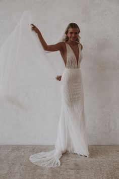 a woman in a white wedding dress holding a veil