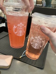 two people holding up cups with drinks in them