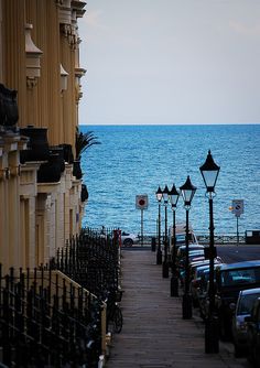 an ocean view from a building next to a street with cars parked on the sidewalk