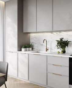 a kitchen with white cabinets and marble counter tops, along with a gold faucet