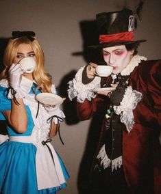 two people dressed up as alice and the mad hatter drinking from coffee mugs