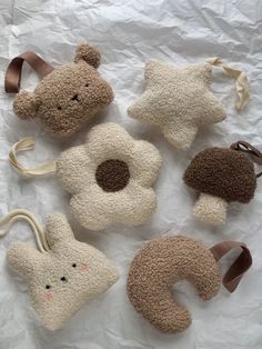 four stuffed animals are laying on a white sheet with brown ribbon around their necks and ears