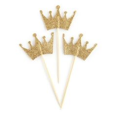 three gold glittered crowns on top of toothpicks in the shape of hearts