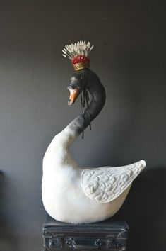 a statue of a swan with a crown on it's head sitting next to a suitcase