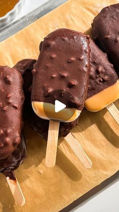 three chocolate covered ice creams on sticks